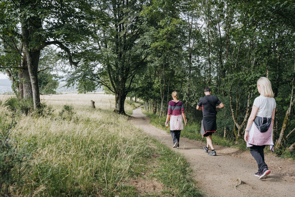 3 Menschen wandern in ihrem Vulkaneifel Urlaub entlang des Wanderweges Heimatspur MaareGlück